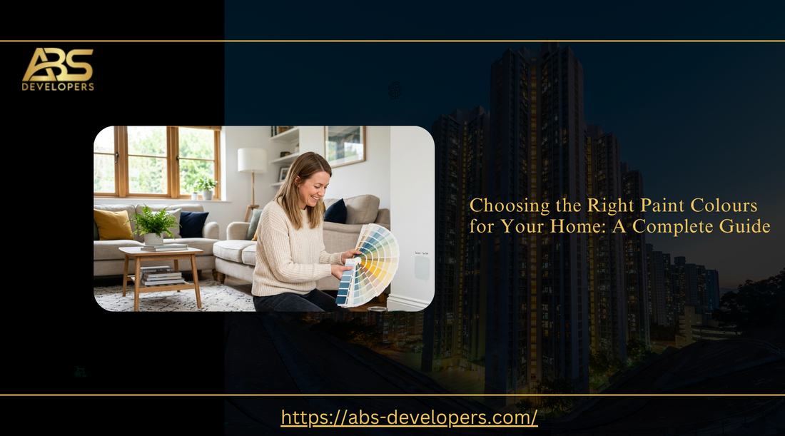 A professional banner for a guide titled "Choosing the Right Paint Colours for Your Home: A Complete Guide." It features a woman looking at a color swatch in a modern living room, with the ABS Developers logo and website link.